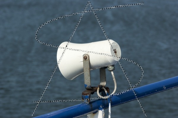 Ein weißer Außenlautsprecher am blauen Schiffsgeländer